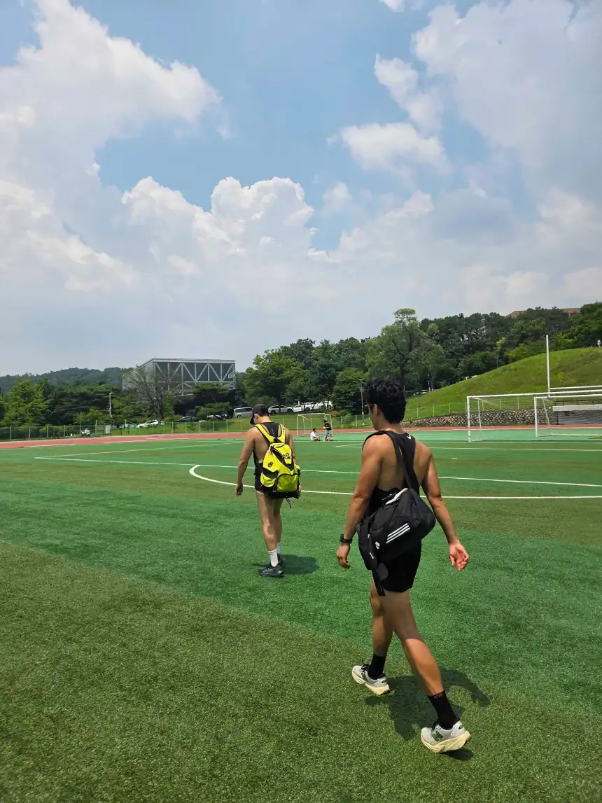 운동장을 가로질러 걸어가는 두 사람의 뒷모습