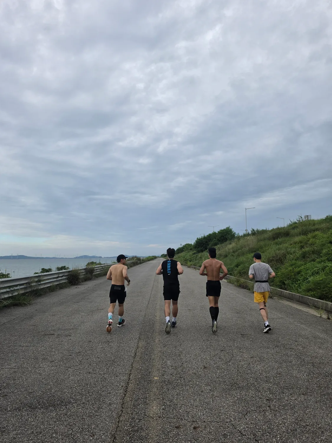 넓은 방조제 길을 나란히 달리는 네 명