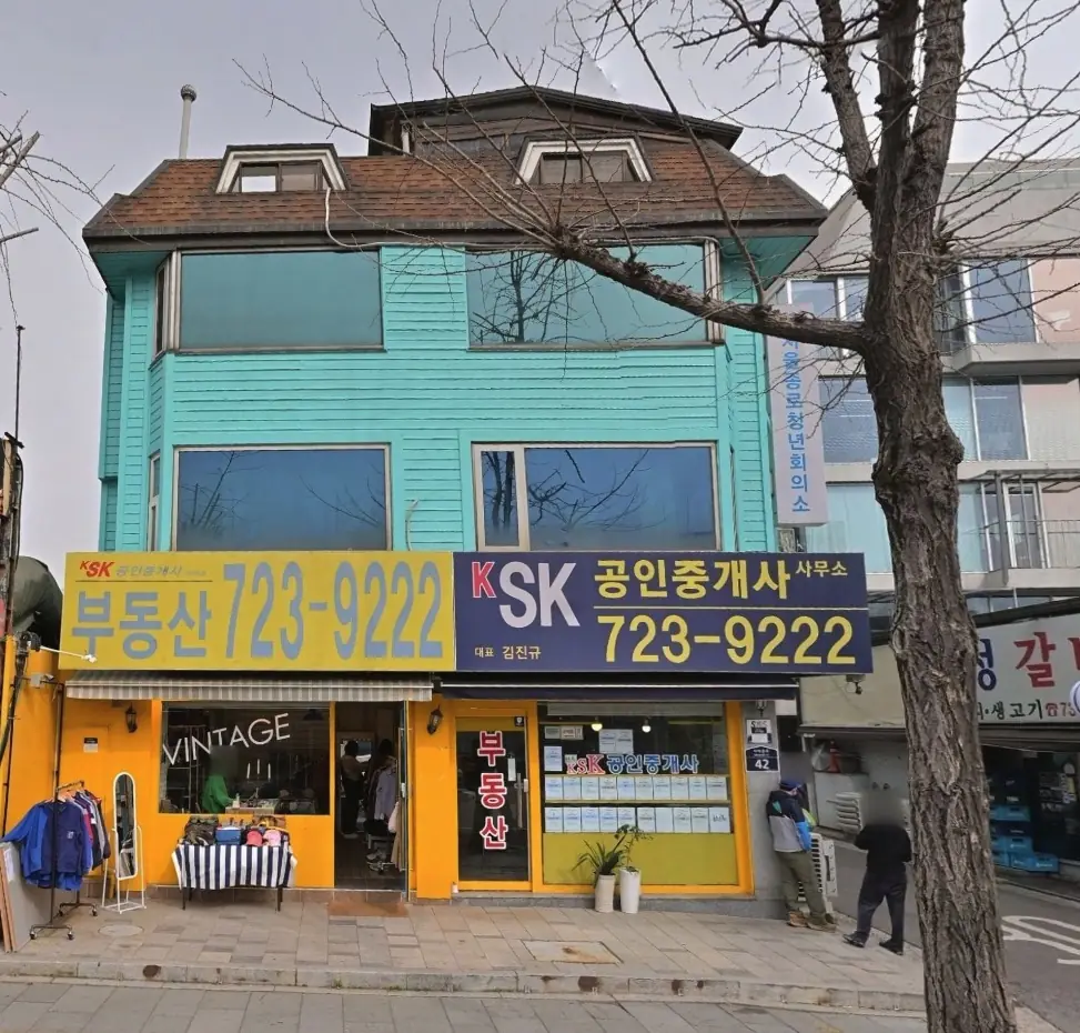 2025년 3월 푸른 외벽과 노란 상점 입구가 보이는 건물